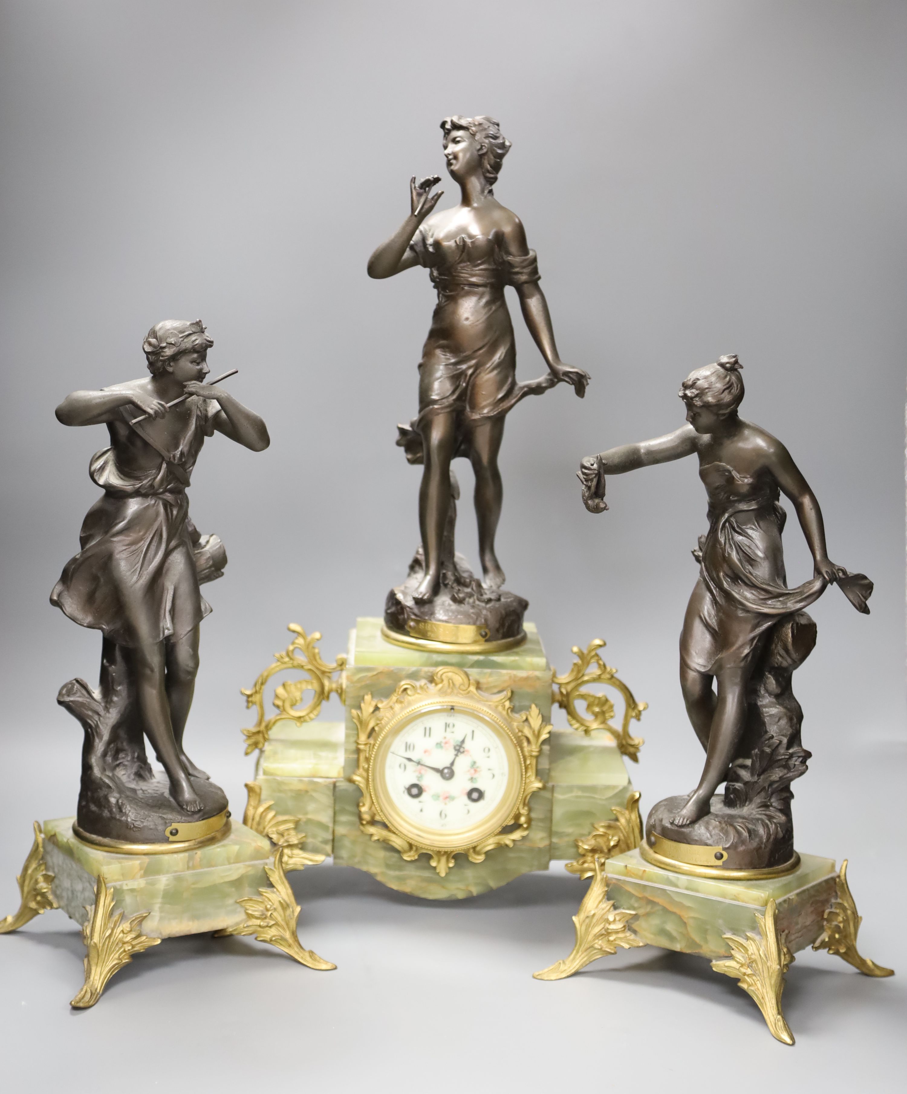 A French onyx and spelter figural clock garniture after Ferrand, plaques read Improvisateur Prisonniere and Sensitive, height 50cm